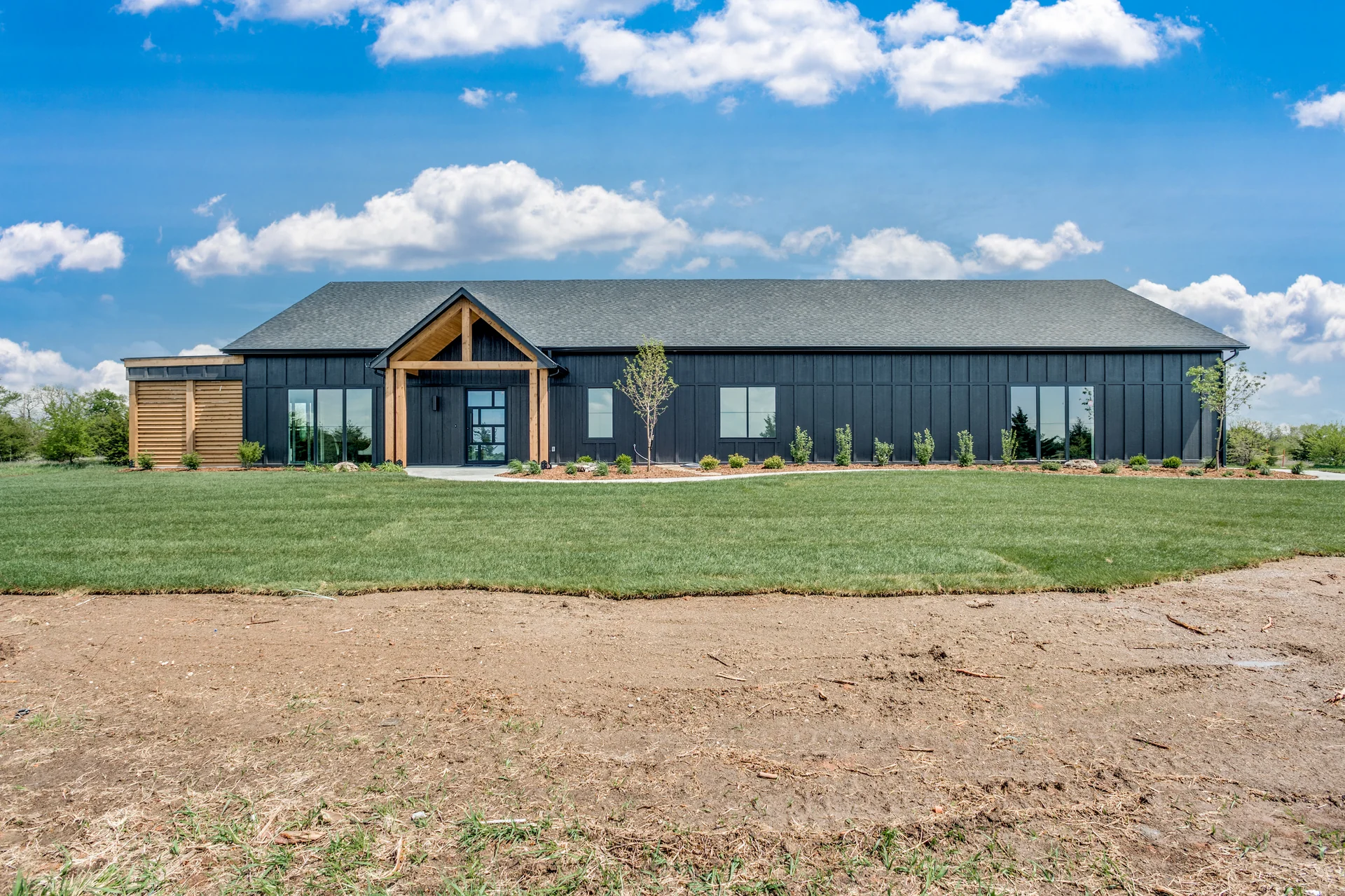 Single-level Sharp Homes house with dark board-and-batten siding and a timber-framed entry